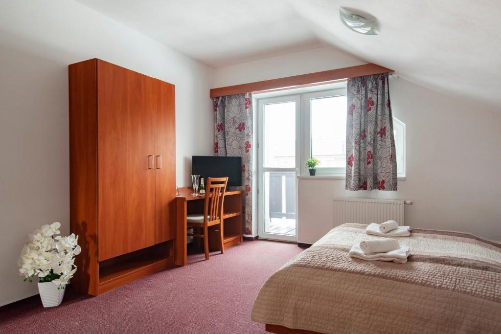 a bedroom with a bed and a window and a desk at Penzión Borievka in Poprad