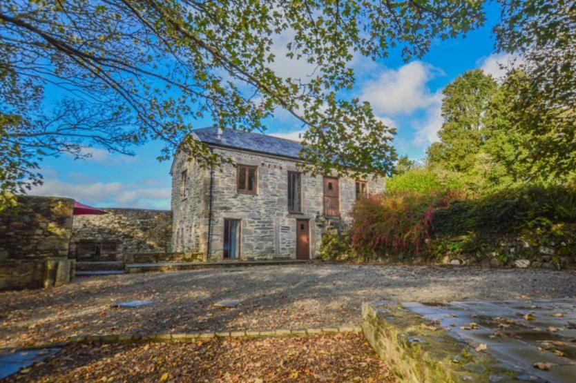 a stone house with a driveway in front of it at The Threshing Barn in Gwennap