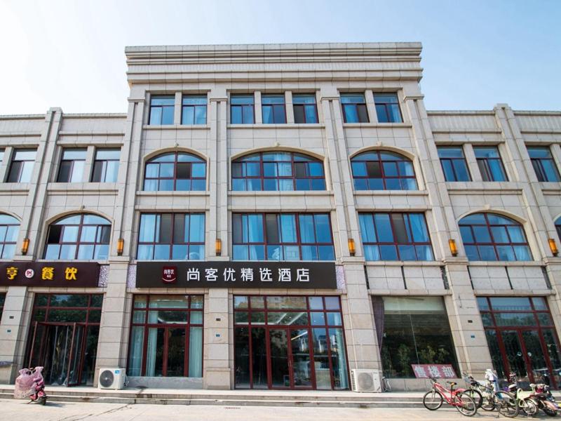 a large building with many windows on a street at Thank Inn Plus Hotel Jiangsu Suqian Diamond Apartment in Suqian