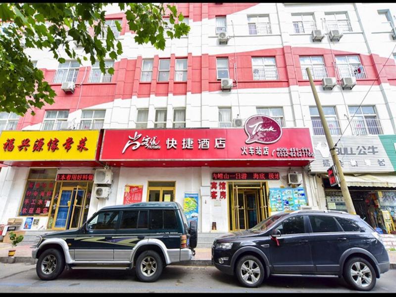 dois carros estacionados em frente a um edifício em Thank Inn Chain Hotel Shandong Qingdao Trestle railway station em Qingdao