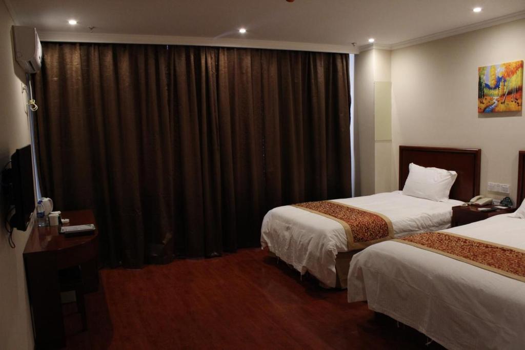 GreenTree Inn Bozhou Mengcheng District Red Star Macalline Business Hotel tesisinde bir odada yatak veya yataklar