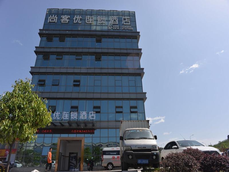 um grande edifício com carros estacionados em frente em Thank Inn Chain Hotel sichuan mianyang yuzhong road airport em Mianyang