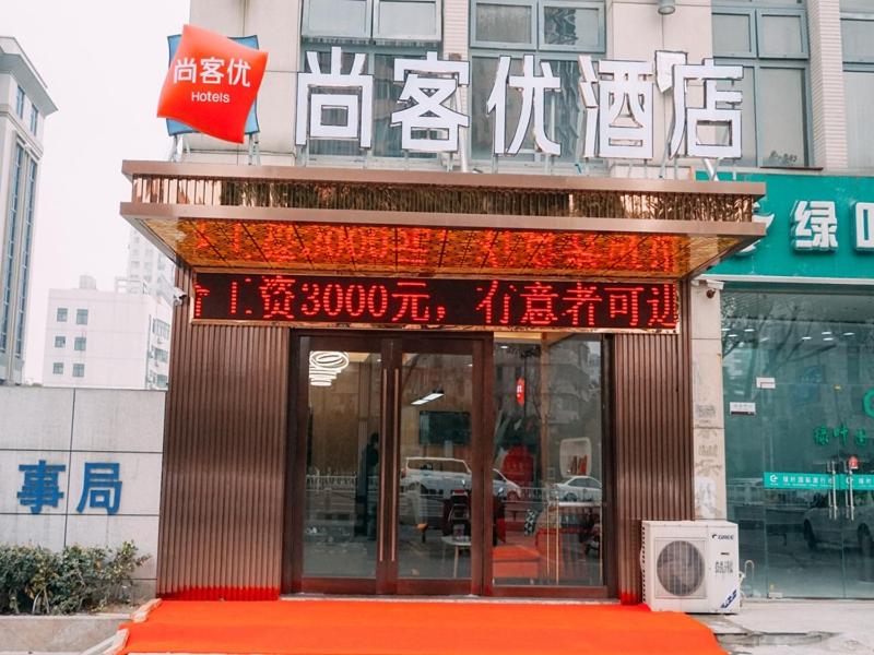 un edificio con un cartel en la parte delantera en Thank Inn Chain Hotel Jiangsu yancheng pavilion lakes open road, en Yancheng
