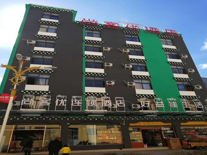 Baima的住宿－尚客优酒店西藏昌都八宿县县政府店，一座黑色和绿色的建筑,里面摆放着椅子