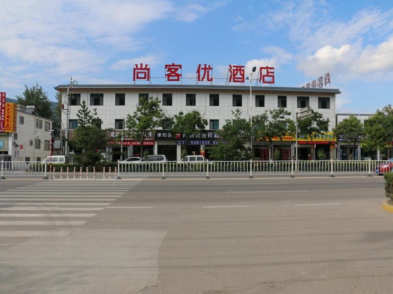 a building with a sign on the side of a street at Thank Inn Chain Hotel gansu tianshui maiji district xihuang avenue in Tianshui