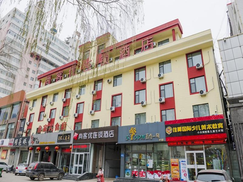 a large building on a city street with buildings at Thank Inn Chain Hotel shanxi jinzhong yuci ditrict no.2 middle school in Jinzhong
