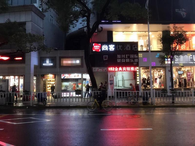 una calle de la ciudad por la noche con gente parada frente a tiendas en Thank Inn Chain Hotel jiangxi nanchang zhongshan road August 1st pavilion mero station en Nanchang