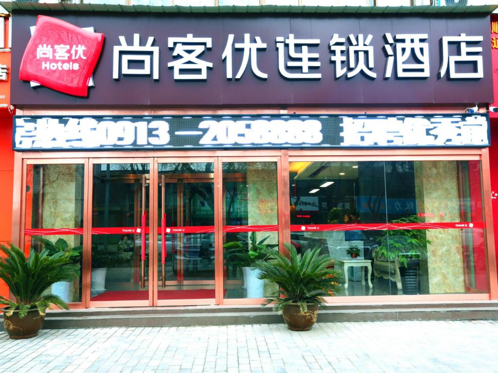uma loja em frente a um restaurante com plantas em frente em Thank Inn Chain Hotel shanxi weinan linwei district jiefang road em Weinan