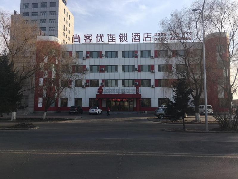 duży biały budynek z chińskim napisem w obiekcie Thank Inn Chain Hotel Heilongjiang qiqihar Longsha District Middle Hospital High-Speed Railway South Station w Qiqihar
