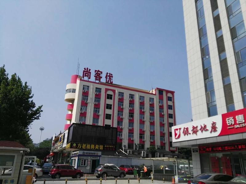 een groot gebouw met Chinees schrift erop bij Thank Inn Chain Hotel shandong yantai zhifu district RT-Mart railway station in Yantai