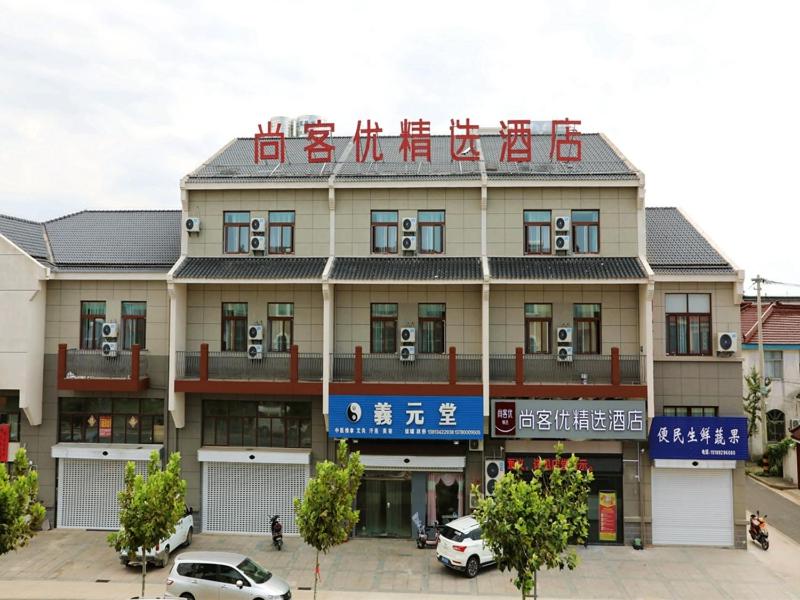 a building with cars parked in front of it at Thank Inn Chain Hotel Jiangsu Yancheng dongtai Jianggang town in Cuiguangshan