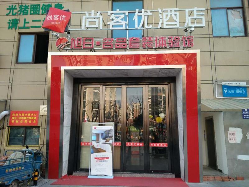 un bâtiment avec une entrée rouge et blanche à un magasin dans l'établissement Thank Inn Chain Hotel jiangsu taizhou hailing district yingchun road, à Taizhou