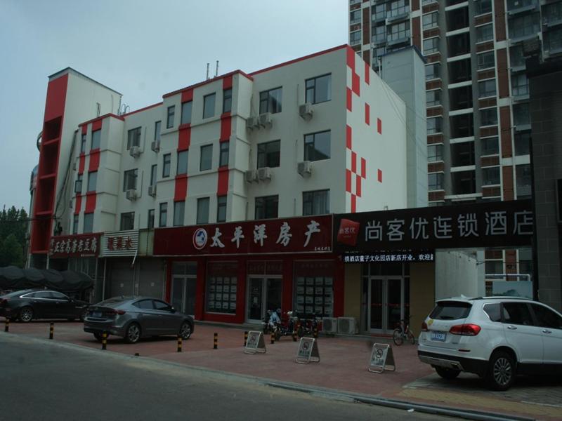 budynek z samochodami zaparkowanymi przed nim w obiekcie Thank Inn Chain Hotel shandong dezhou development zone dongzi cultural park w mieście Dezhou