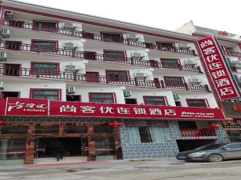 a large white building with red signs on it at Thank Inn Chain Hotel guizhou anshun huangguoshu scenic area in Anshun