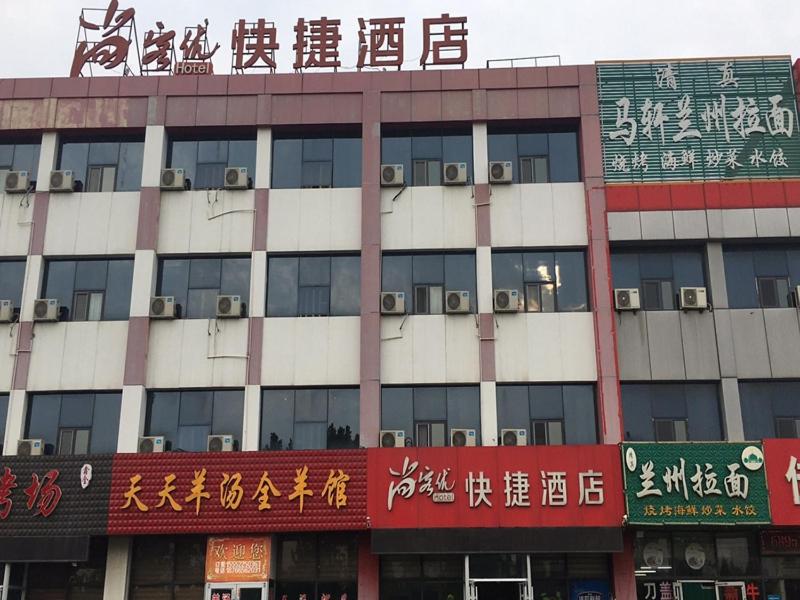 un gran edificio con letreros en el costado en Thank Inn Chain Hotel shandong yantai high-speed railway sounth station, en Yantai