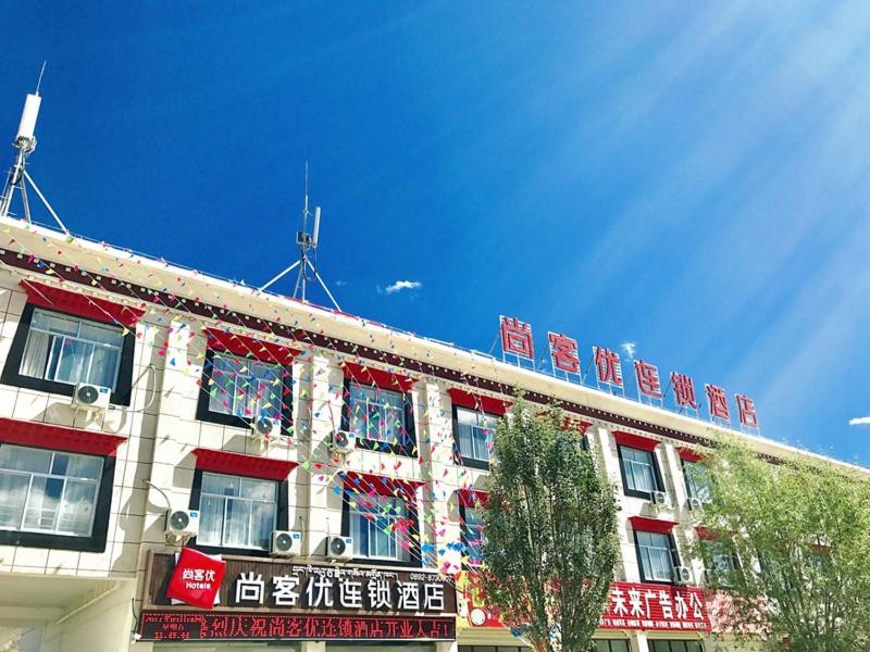a building with red and white signs on top of it at Thank Inn Chain Hotel tibet shigatse angren county government in Kaika