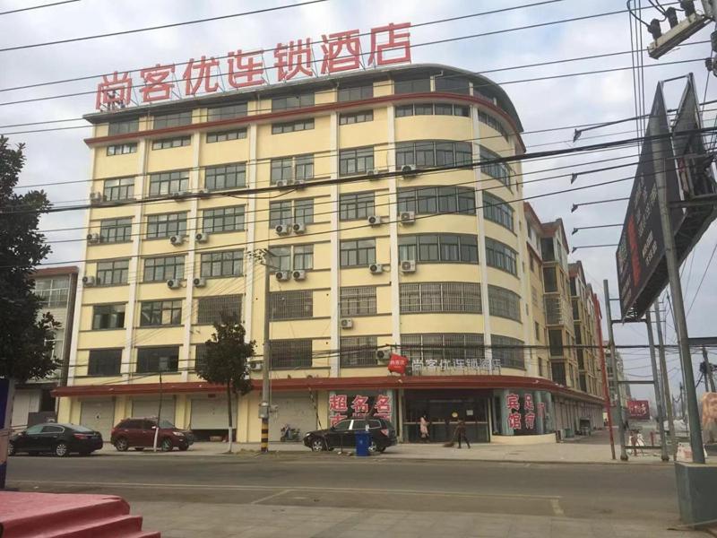een groot gebouw met een bord erop bij Thank Inn Chain Hotel jiangsu lianyungang donghai county tuofeng town baitabu airport in Lianyungang