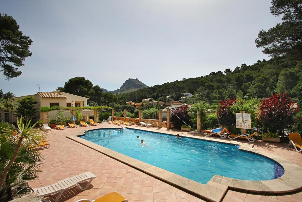 a large swimming pool with chairs and a mountain at PINOS ALTOS 11 in Cala de Sant Vicenc