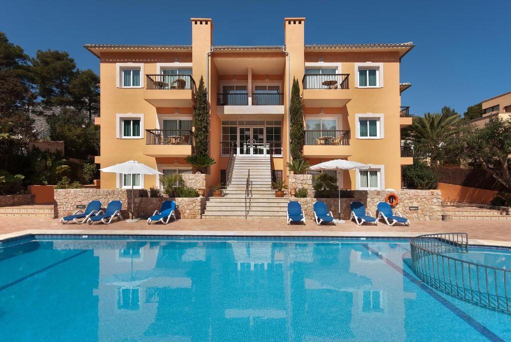 a hotel with a swimming pool in front of a building at PINOS ALTOS 15 in Cala de Sant Vicent