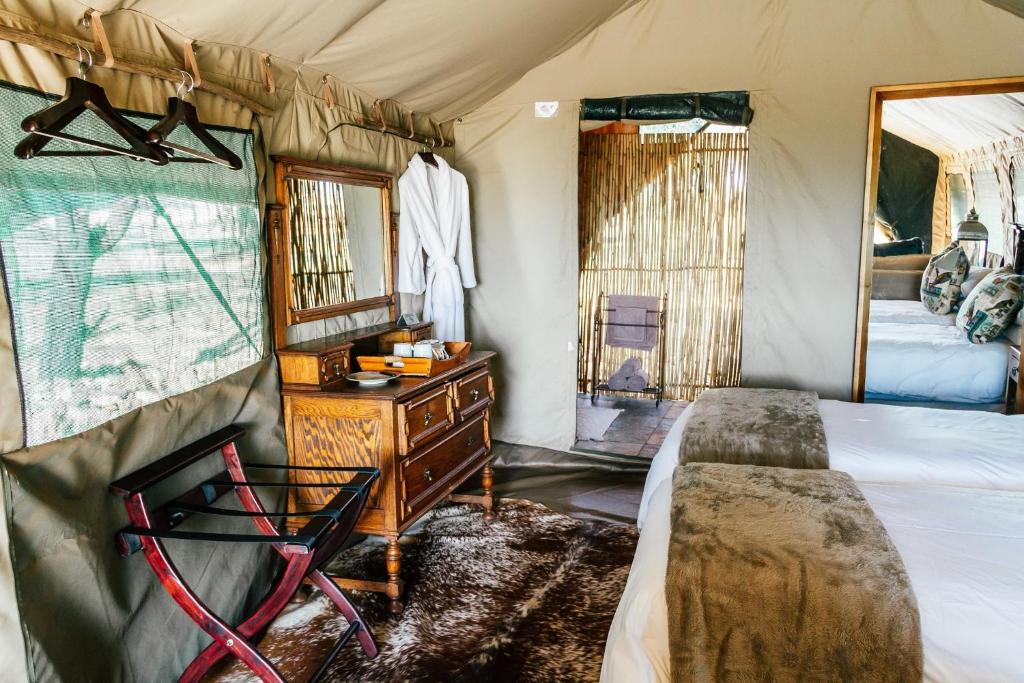 Schlafzimmer mit einem Bett, einer Kommode und einem Spiegel in der Unterkunft Sibani Lodge - Glamping Tents in Krugersdorp