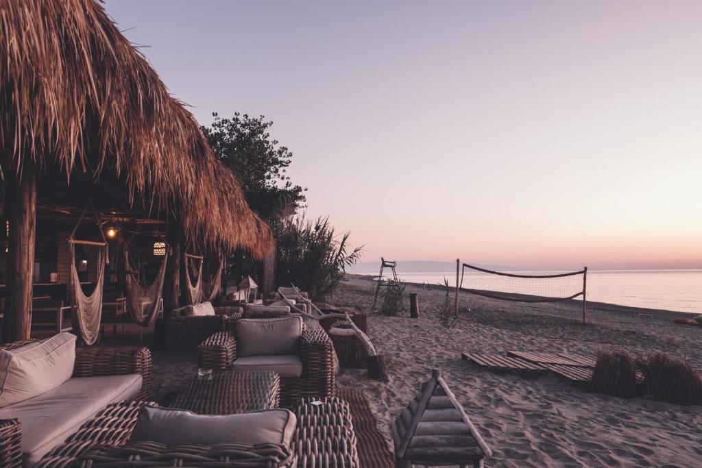 una spiaggia con molti divani e sedie sulla sabbia di Riva del Sol Beach Resort a Santa Caterina dello Ionio