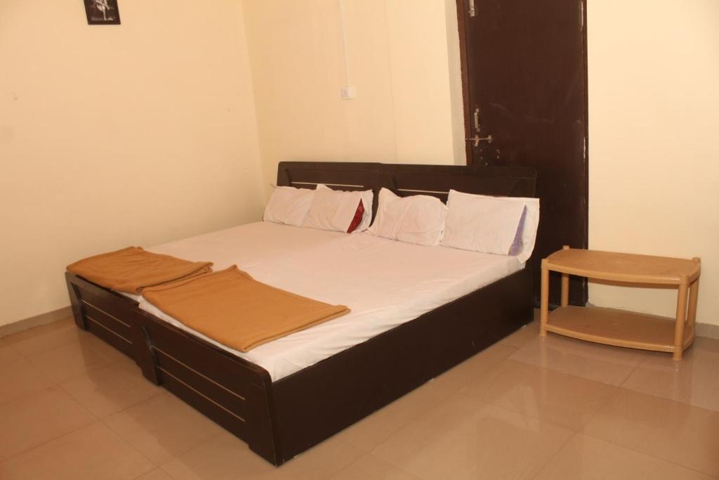a bed with a black frame and white sheets and pillows at Hotel Sai Satya in Shirdi