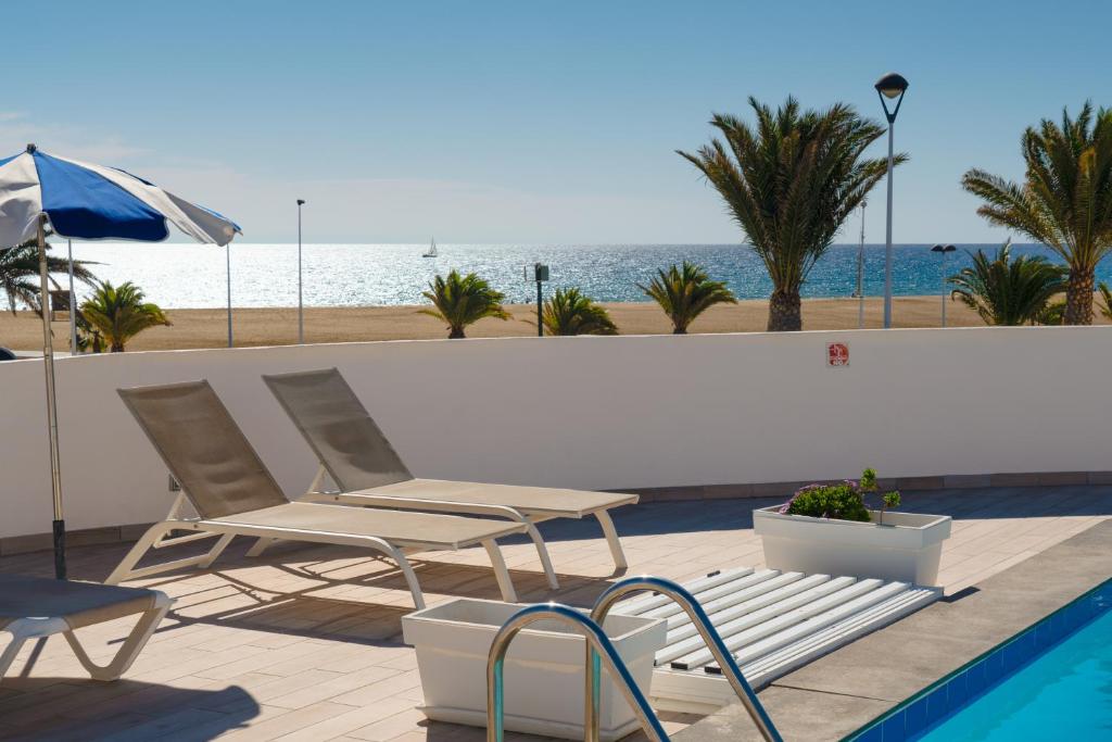 duas cadeiras e um guarda-sol junto a uma piscina em Villa Ventura em Puerto del Carmen