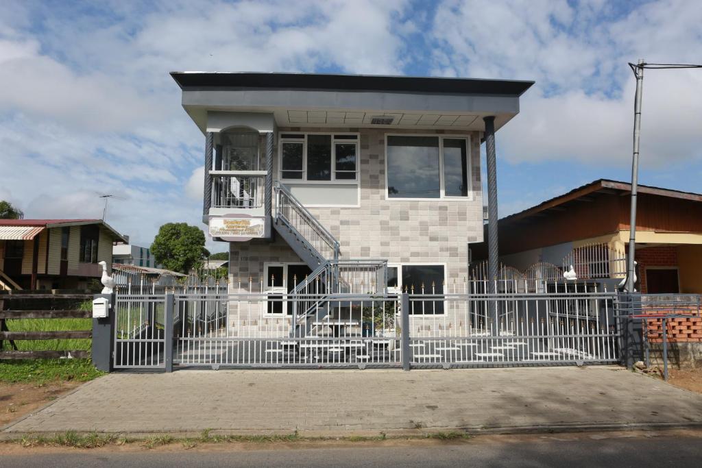 una casa blanca con una valla delante en Donfarsha Apartments, en Paramaribo