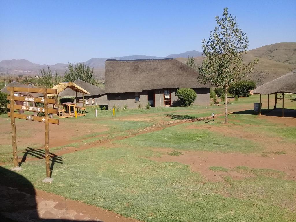 a building with a thatched roof in a field at Ribaneng Lodge in Ribaneng