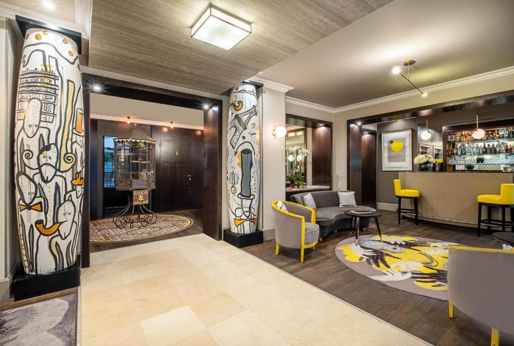 a lobby with a bar with yellow chairs at Hôtel Le Marquis by Inwood Hotels in Paris