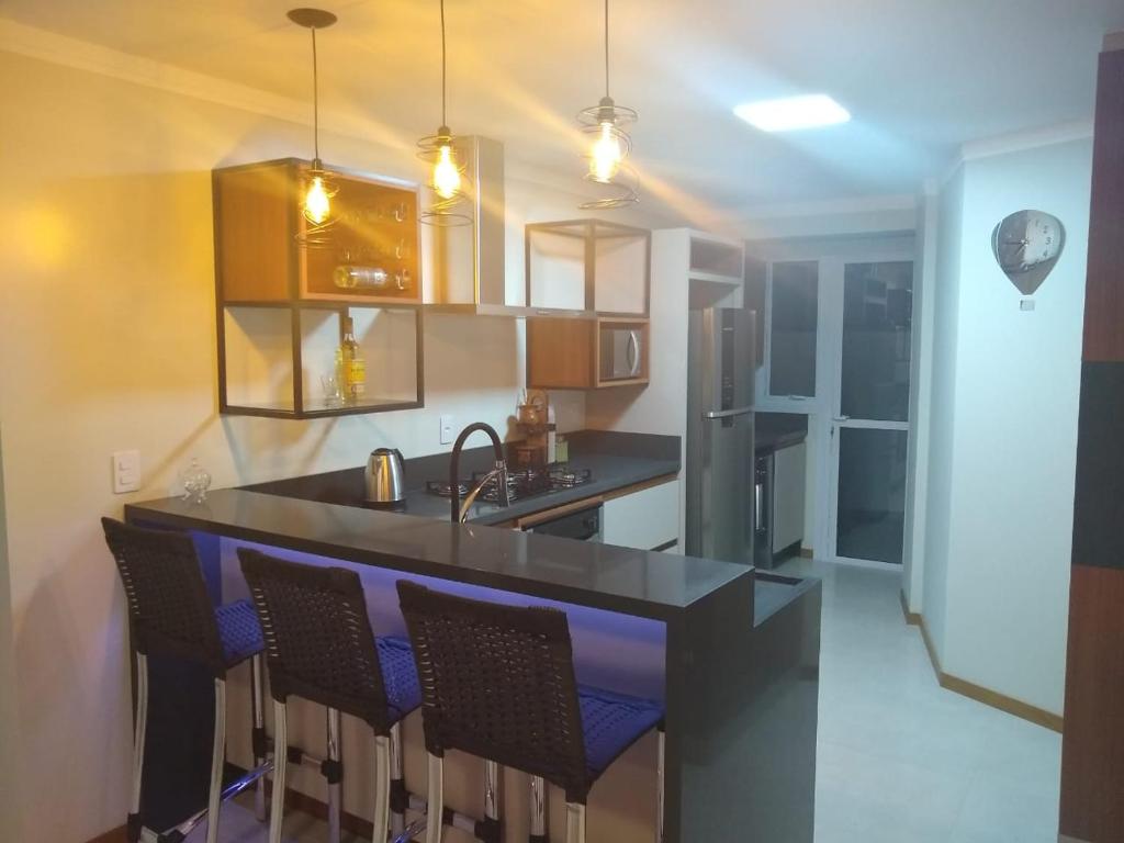 a kitchen with a bar with chairs in it at Apartamento super confortável, Torres RS in Torres