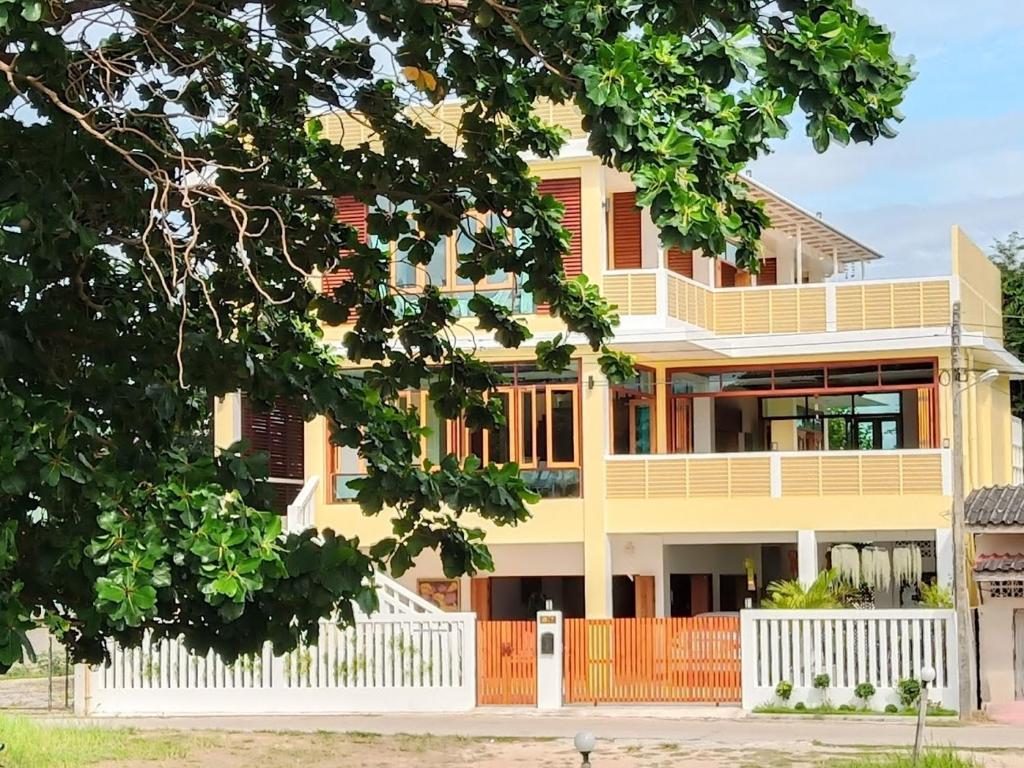 une grande maison jaune avec une clôture blanche dans l'établissement Yen~Yen B&B, à Prachuap Khiri Khan