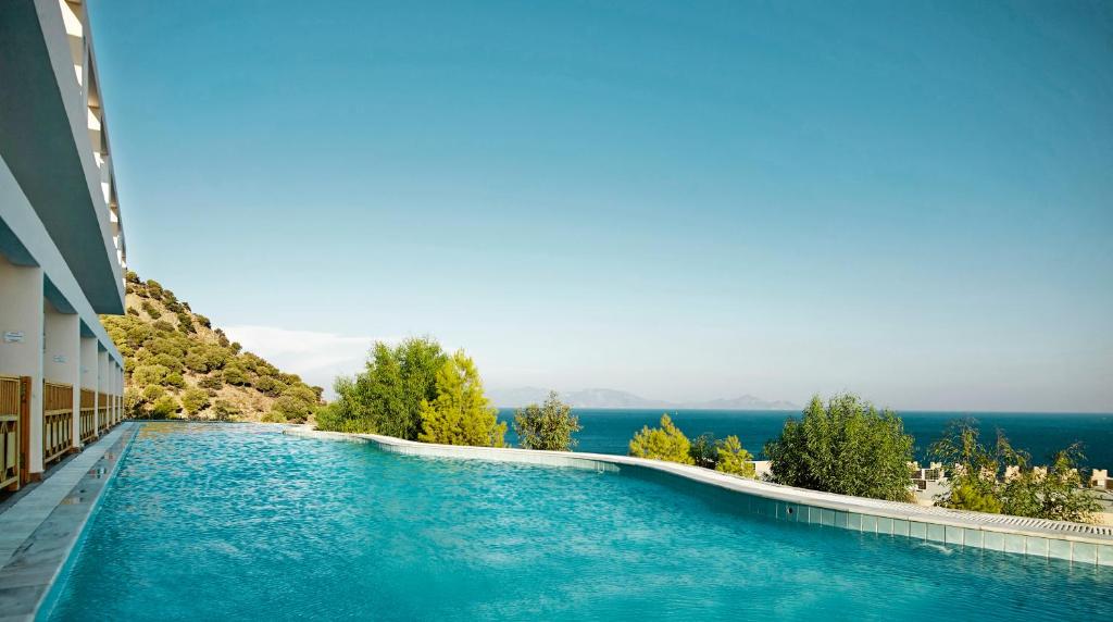 a swimming pool in a building with blue water at Mitsis Family Village in Kardamaina