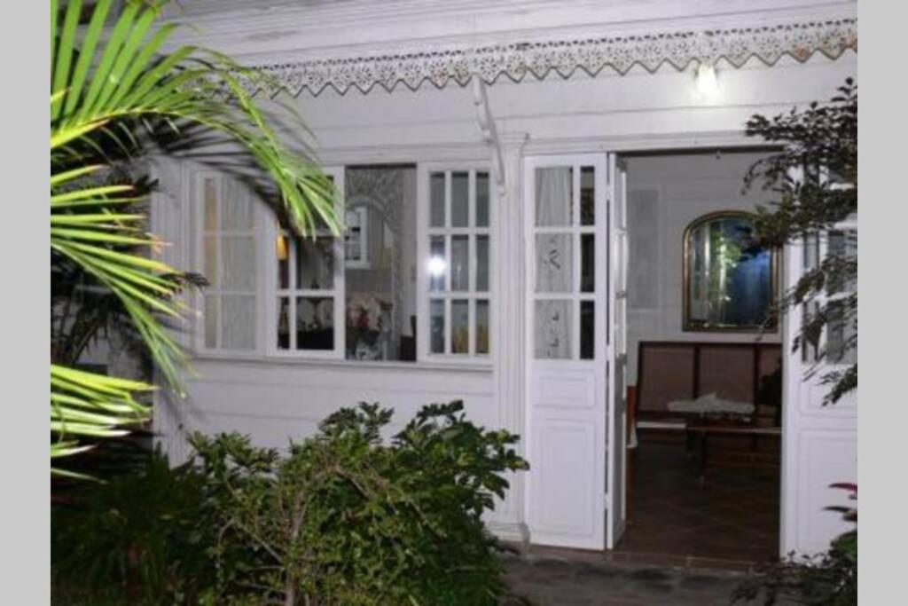 une maison blanche avec une porte et une terrasse couverte dans l'établissement Villa CASE LONTAN Saint Gilles les Bains, à Saint-Gilles les Bains