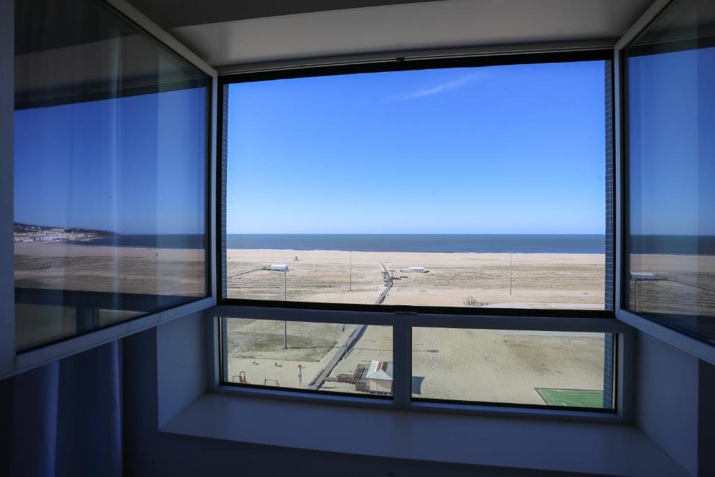 an empty room with a window with a view of the beach at Sea Side Luxury Apartment in Figueira da Foz