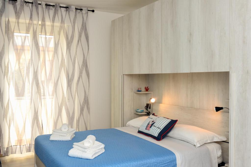 sypialnia z niebieskim łóżkiem i oknem w obiekcie B&B LaMarina w mieście Alghero
