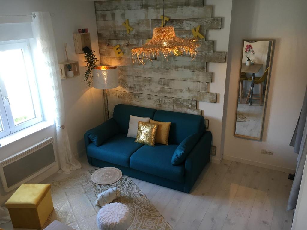 a living room with a blue couch and a chandelier at Un petit coin de paradis au centre ville de Caen in Caen