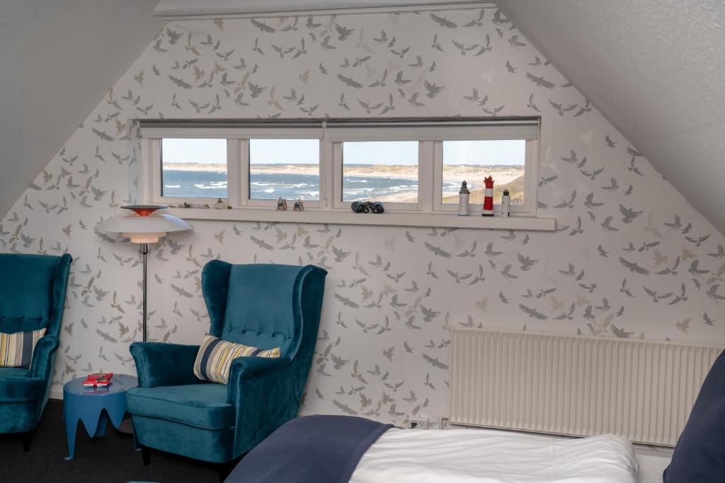 a bedroom with a bed and two chairs and a window at Klitmøller Hotel in Klitmøller