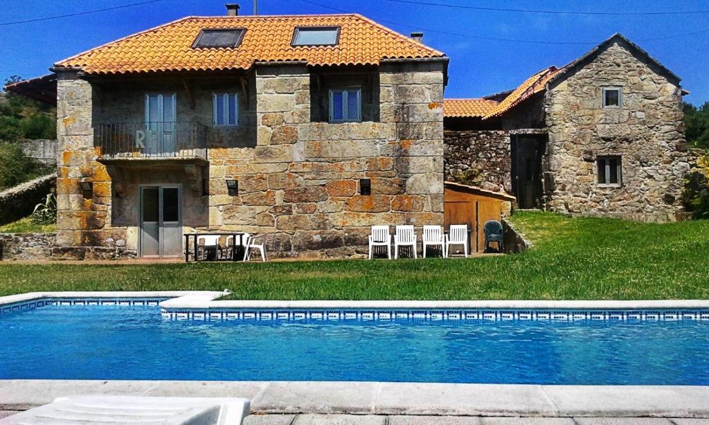 a building with a swimming pool in front of a house at Rectoral de Prado in Piñeiro