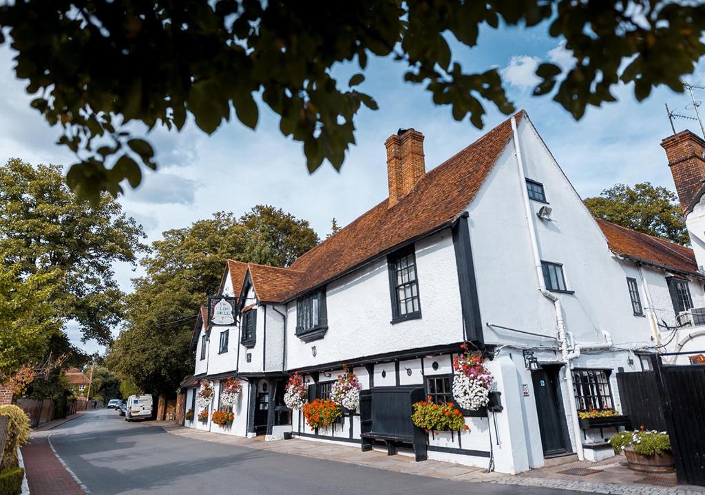 a white building with flowers in front of a street at The Olde Bell in Marlow