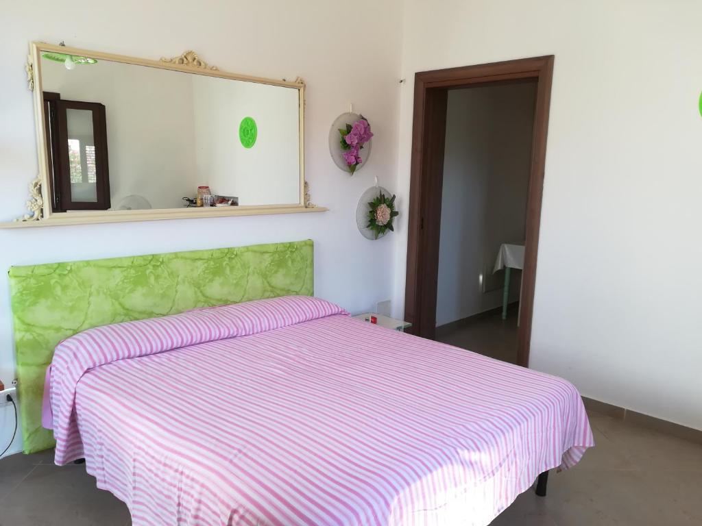 una camera con un letto con una coperta a righe rosa e bianche di Stanza B&B Posto Rosso a Torre San Giovanni Ugento