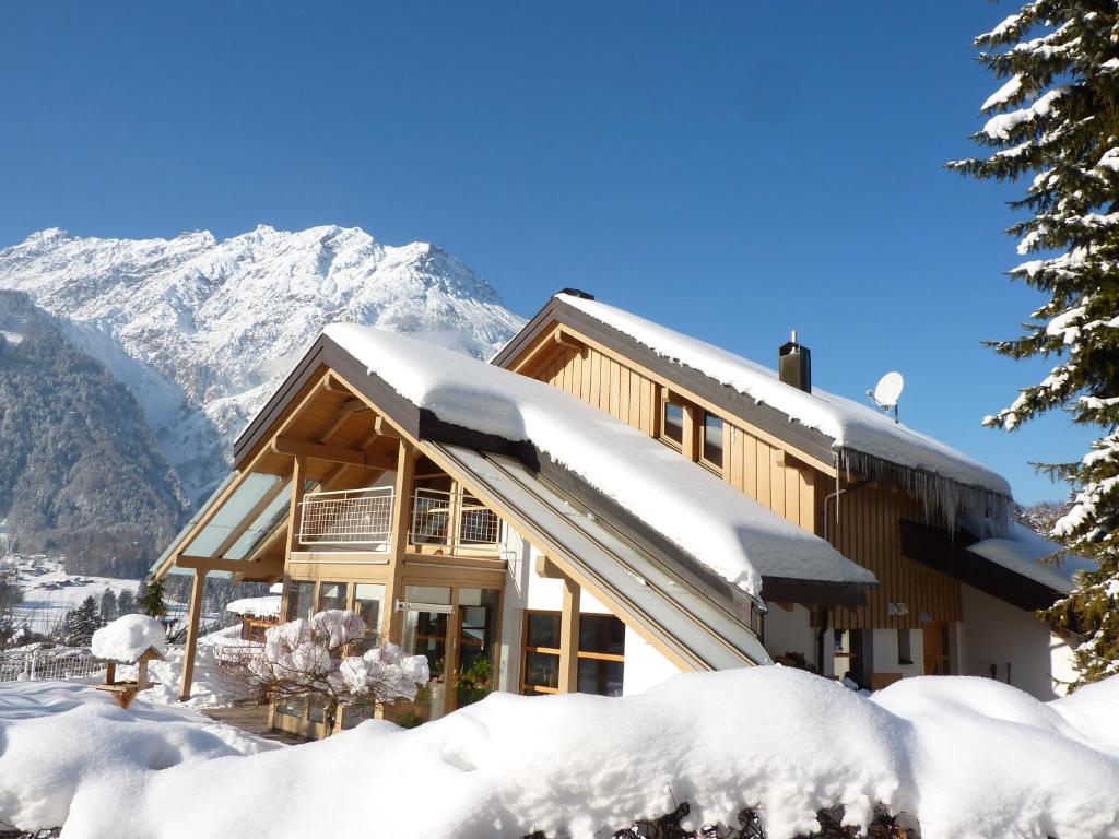 ein schneebedecktes Haus mit Bergen im Hintergrund in der Unterkunft Haus am Wasserfall in Sankt Anton im Montafon
