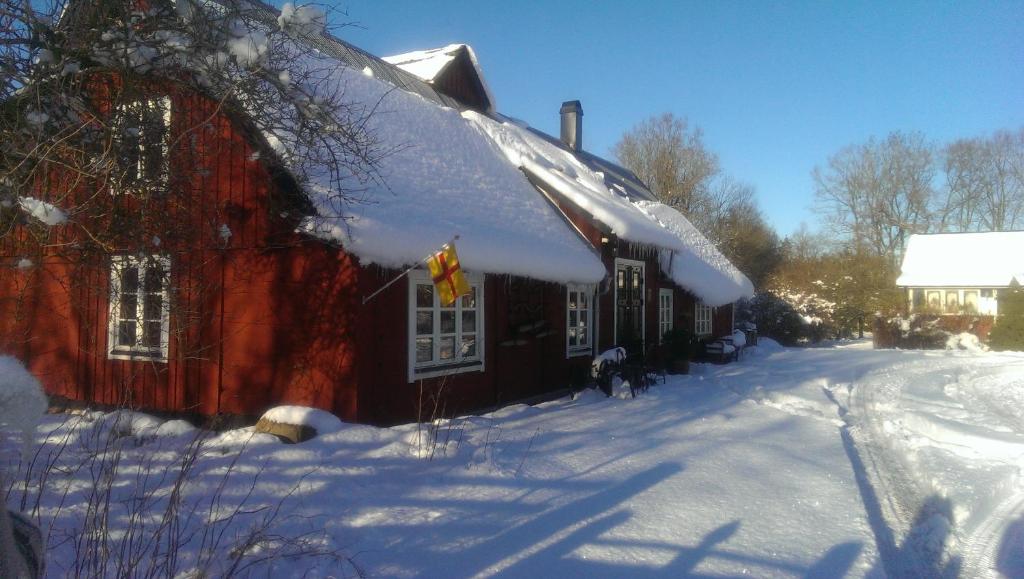 a red barn with snow on the roof at Rögnaröd 4604 in Ljungbyhed