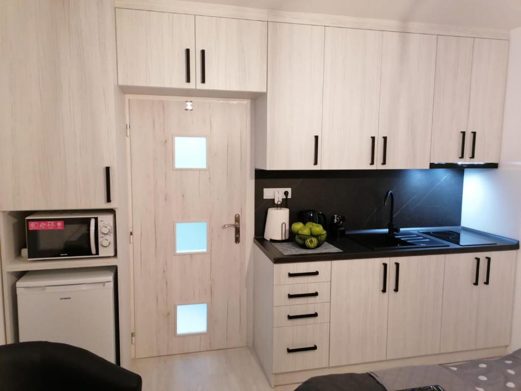 a kitchen with white cabinets and a door with a microwave at Apartment Nina in Stará Ľubovňa