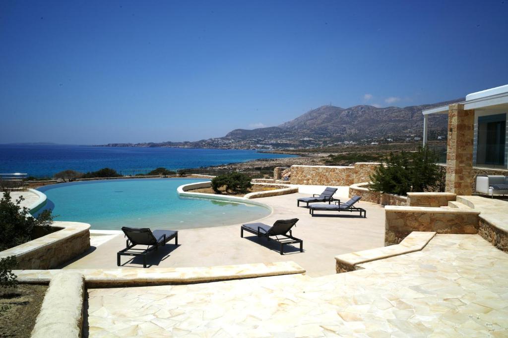 a swimming pool with chairs and a view of the water at Villa Chelidonia in Karpathos