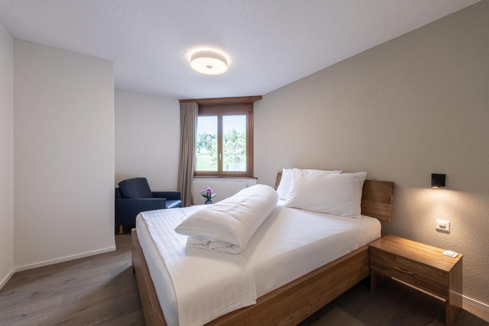 a bedroom with a bed with white sheets and a window at Noah Hotel in Rüti