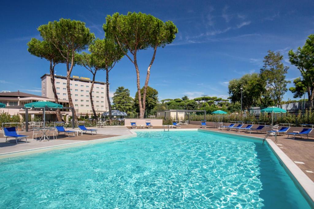 una piscina con sedie e ombrelloni in un hotel di Hotel Cristoforo Colombo a Roma