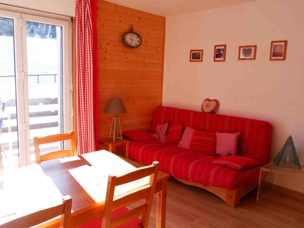 a living room with a red couch and a table at Romantic Chalet-Style Flat with Mountain View in Torgon