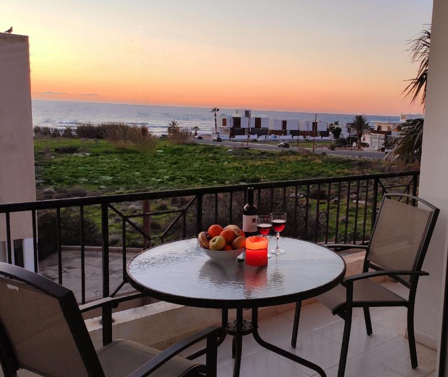 un tavolo con un cesto di frutta e bicchieri da vino sul balcone di Lighthouse Beach apartment a Paphos