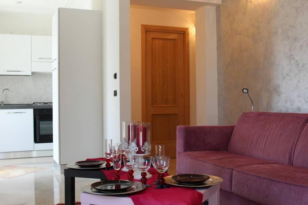 un soggiorno con divano viola e tavolo con bicchieri da vino di coreno luxury ad Ausonia